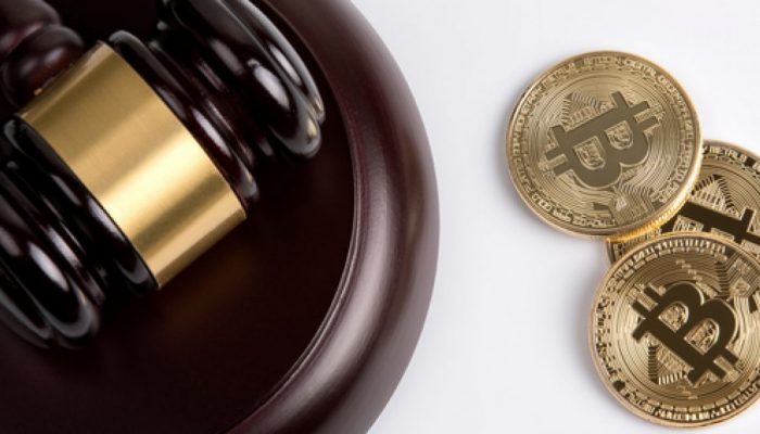 Picture of a gavel and sound block with three bitcoins right next to it